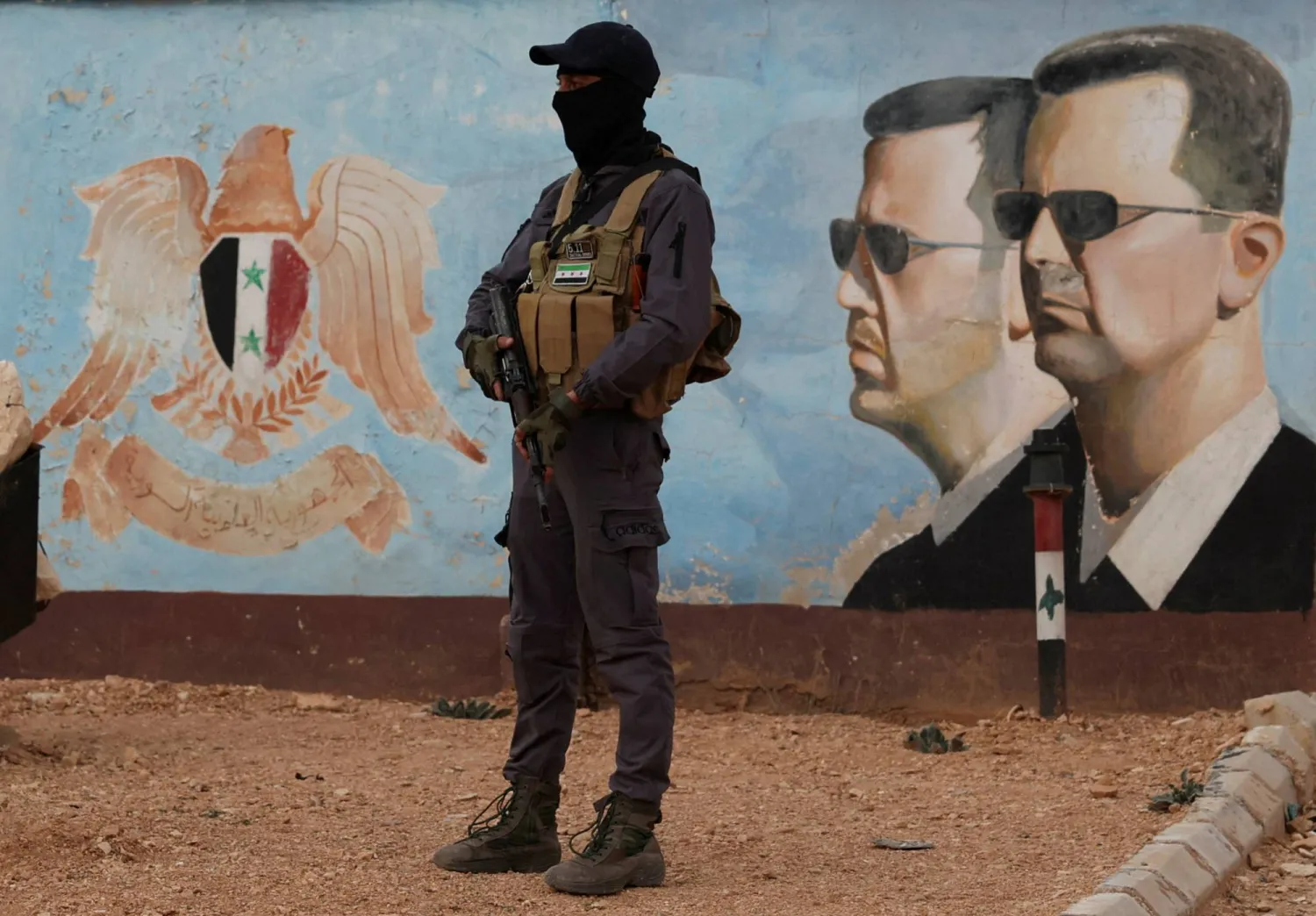 FILE PHOTO: A member of the former rebel group Hayat Tahrir al-Sham stands guard near an image of Syria's Bashar al-Assad at the fourth division headquarters in Damascus, Syria, January 23, 2025 REUTERS/Yamam Al Shaar/File Photo