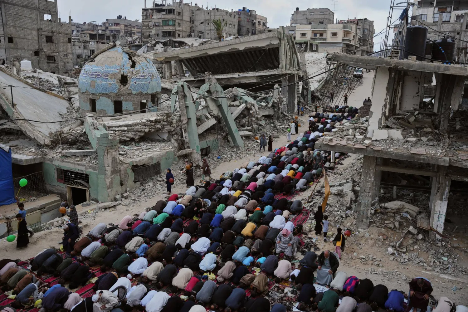 فلسطينيون يؤدون صلاة عيد الأضحى بجوار أنقاض مسجد دمره القصف الإسرائيلي في خان يونس (أ.ب)