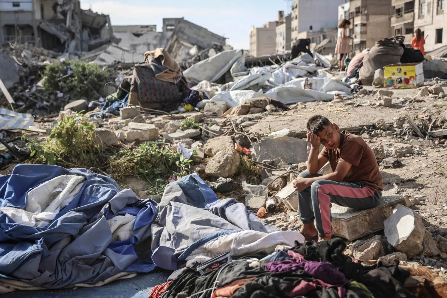 فتى فلسطيني يجلس في المكان الذي استهدف بغارة إسرائيلية أودت ليل أمس بحياة 10 أشخاص في مدينة غزة (أ.ف.ب)