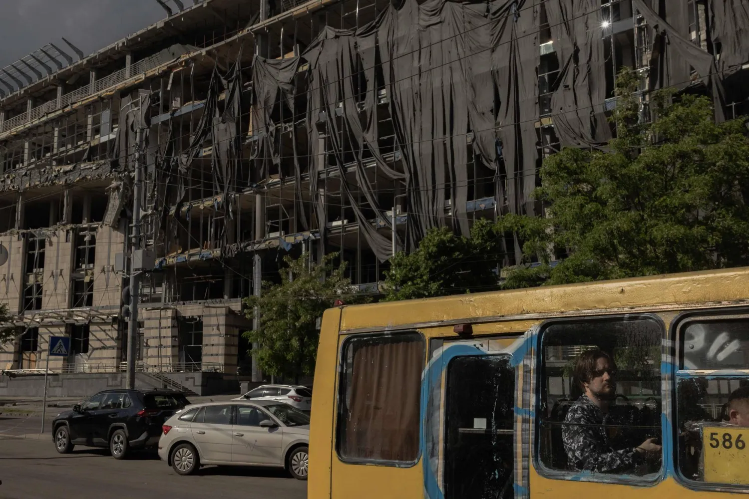Commuters sit in a bus driving past a heavily damaged building following Russian strikes near the Lukianivska metro station in Kyiv on May 27, 2026, amid the Russian invasion of Ukraine. (AFP) 