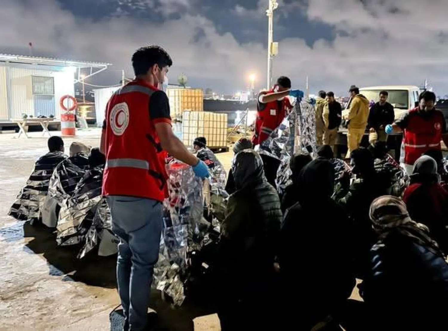 متطوعون من الهلال الأحمر الليبي يقدمون مساعدات إنسانية لمهاجرين غير نظاميين في ساحل مدينة طبرق الليبية (الصفحة الرسمية للهلال الأحمر)