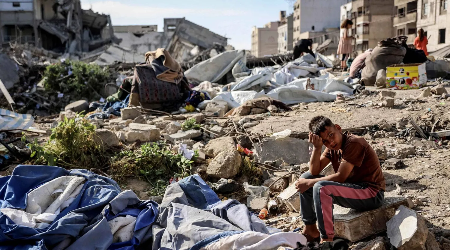  فتى فلسطيني يجلس في المكان الذي استُهدف بغارة إسرائيلية أودت ليل أمس بحياة 10 أشخاص بمدينة غزة (أ.ف.ب)