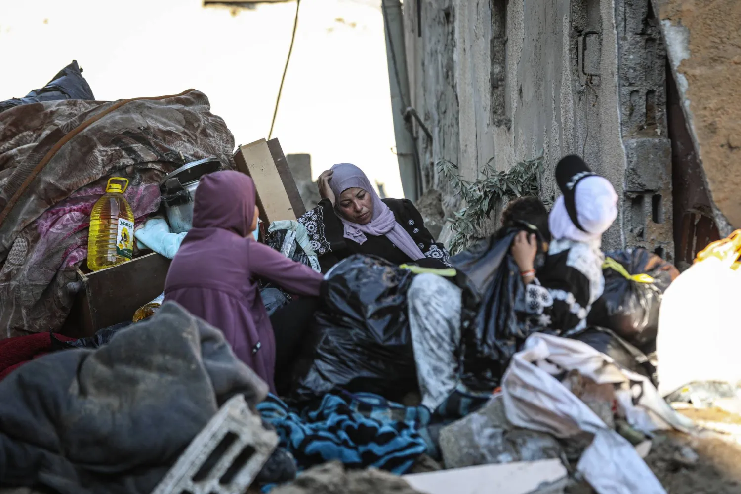 فلسطينيات وسط دمار مبنى استهدفته غارة جوية إسرائيلية في دير البلح وسط قطاع غزة الجمعة (د.ب.أ)