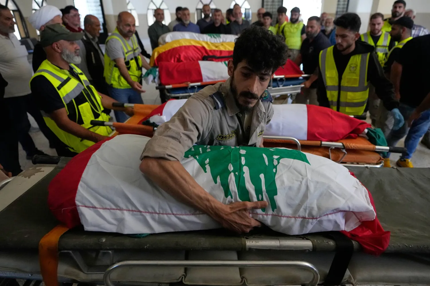 متطوعون في الدفاع المدني ينقلون نعوش 6 مدنيين قتلوا بغارة إسرائيلية أثناء إخلاء بلدتهم في جنوب لبنان (أ.ب)
