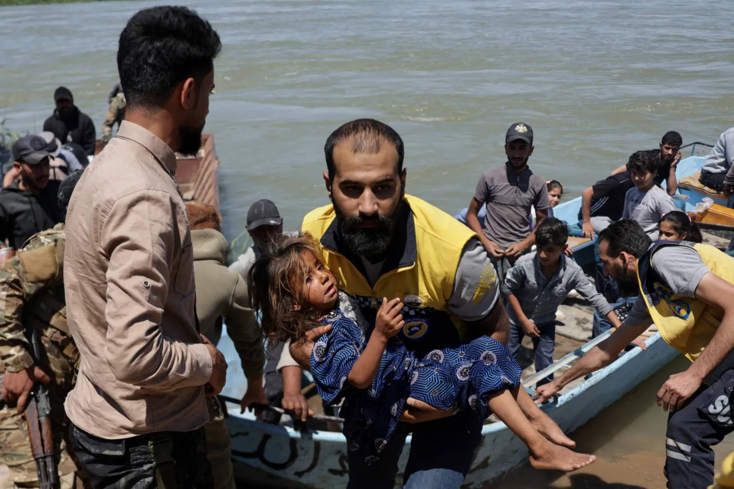 A member of the Syrian Civil Defense, also known as the White Helmets, carries a child after water levels rise due to increased dam releases following heavy rainfall this year, in Deir Ezzor, Syria, May 30, 2026. REUTERS/Khalil Ashawi