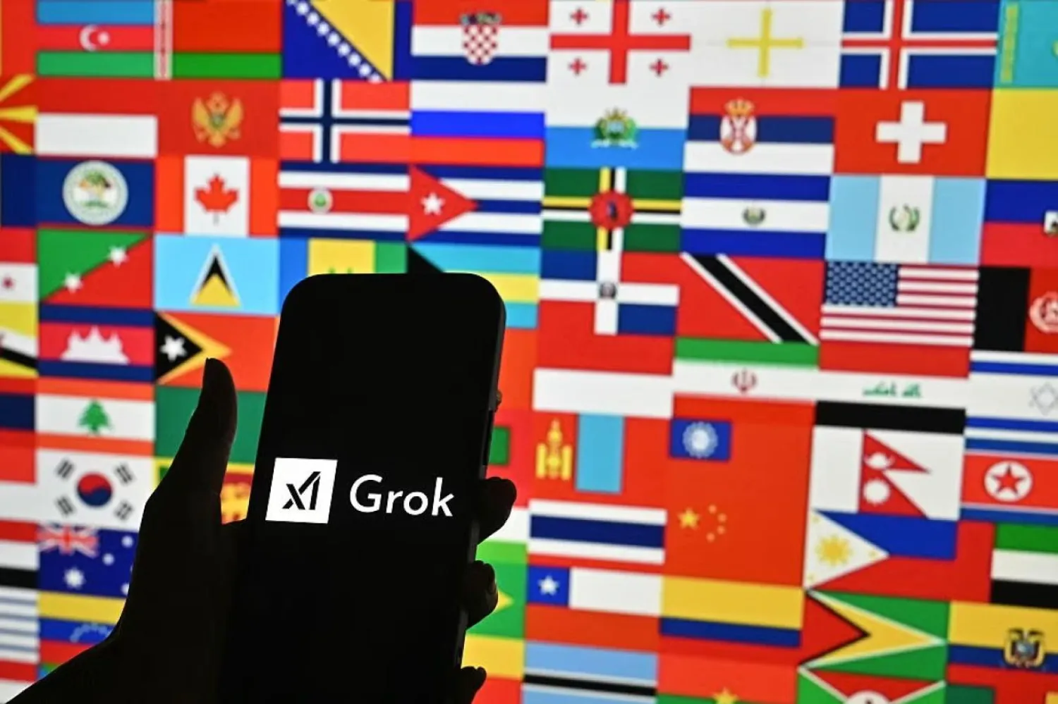 Bir kişi, 15 Ocak 2026'da Bengaluru'da yapay zeka şirketi xAI'ın geliştirdiği üretken yapay zeka sohbet robotu Grok'un logosunu taşıyan akıllı telefonu tutuyor (AFP)