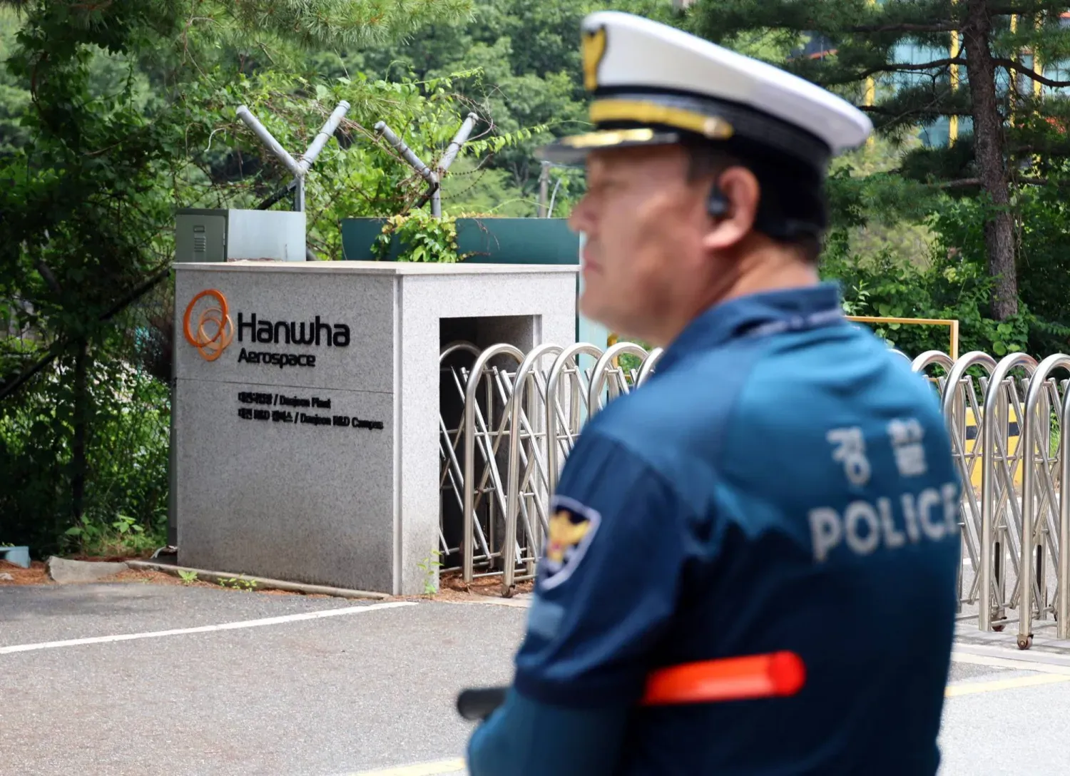 Daejeon'da patlamanın ardından alev alan fabrikanın ana giriş kapısının önünde bir polis memuru duruyor (Reuters)