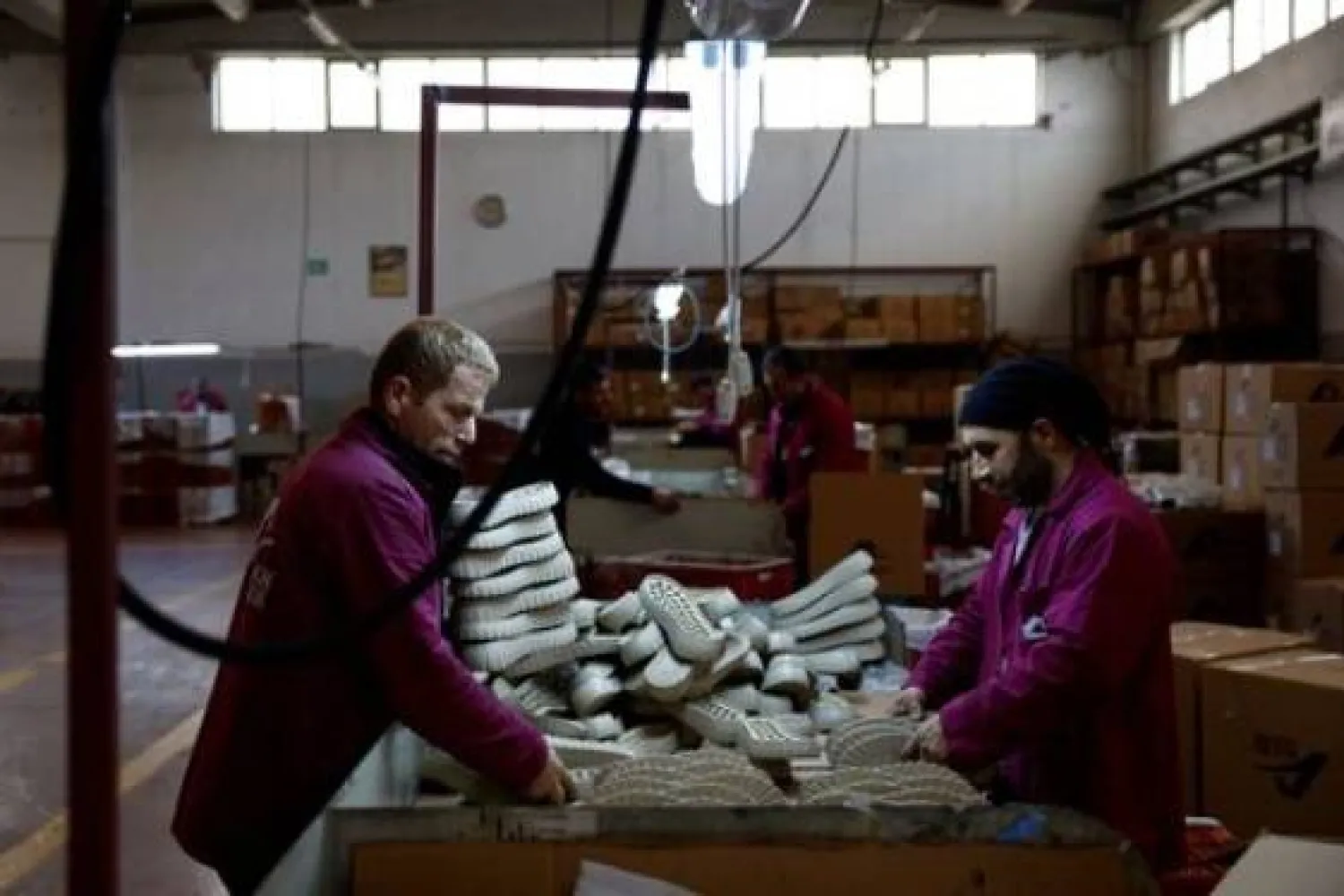 عمال في مصنع شركة «ألكان» لتصنيع نعال الأحذية يعملون داخل المصنع في مجمع «أنطاكيا أوزماني» بولاية هاتاي (رويترز)