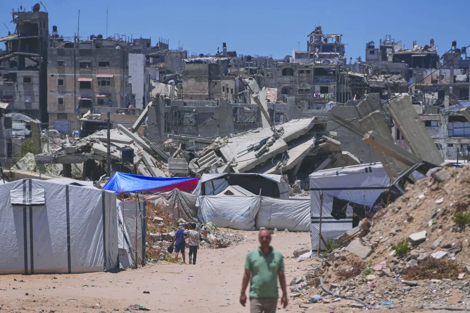 فلسطينيون يسيرون وسط مبانٍ دمَّرتها غارات إسرائيلية في جنوب غزة (أ.ب)