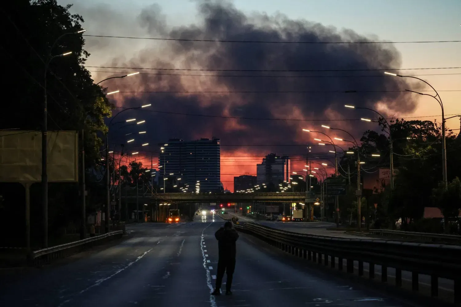  Rusya'nın Ukrayna'nın başkenti Kiev'e düzenlediği gece baskınının ardından yükselen dumanların fotoğrafını çeken bir kişi (Reuters)