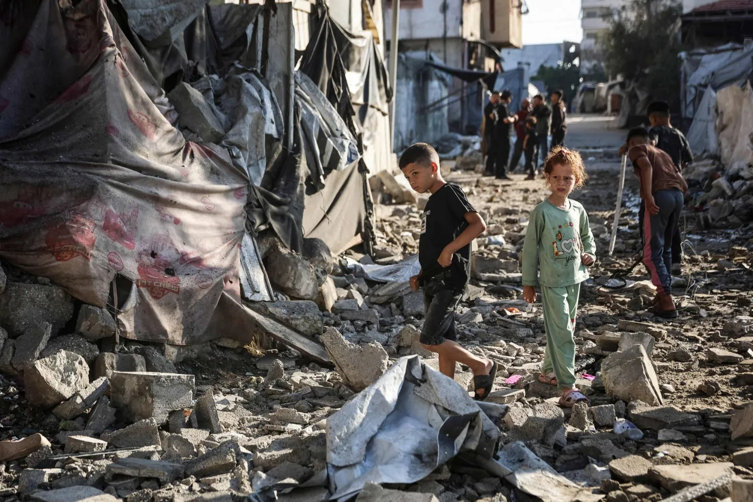 Two Palestinian children walk through the site of an Israeli military strike on structures and tents housing displaced families, killing ten Palestinians, in Gaza City on May 28, 2026. (AFP)