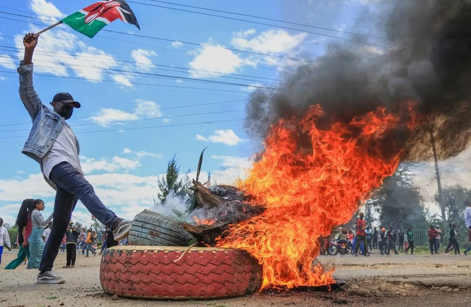  A protester raises a Kenyan flag near a burning barricade during a demonstration against a proposed Ebola quarantine center to be established by the United States at Laikipia Air Base in Nanyuki, Kenya, Monday, June 1, 2026. (AP) 