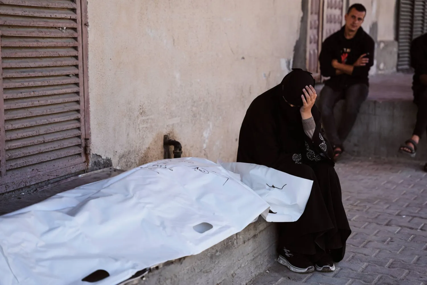 فلسطينية تبكي إلى جوار جثمان قريبها في مستشفى شهداء الأقصى بدير البلح وسط قطاع غزة (رويترز)