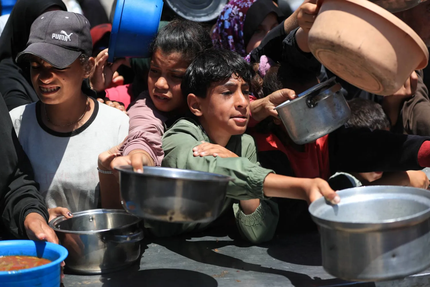 فلسطينيون ينتظرون لتلقي الطعام من مطبخ خيري في مدينة غزة يوم الثلاثاء (رويترز)