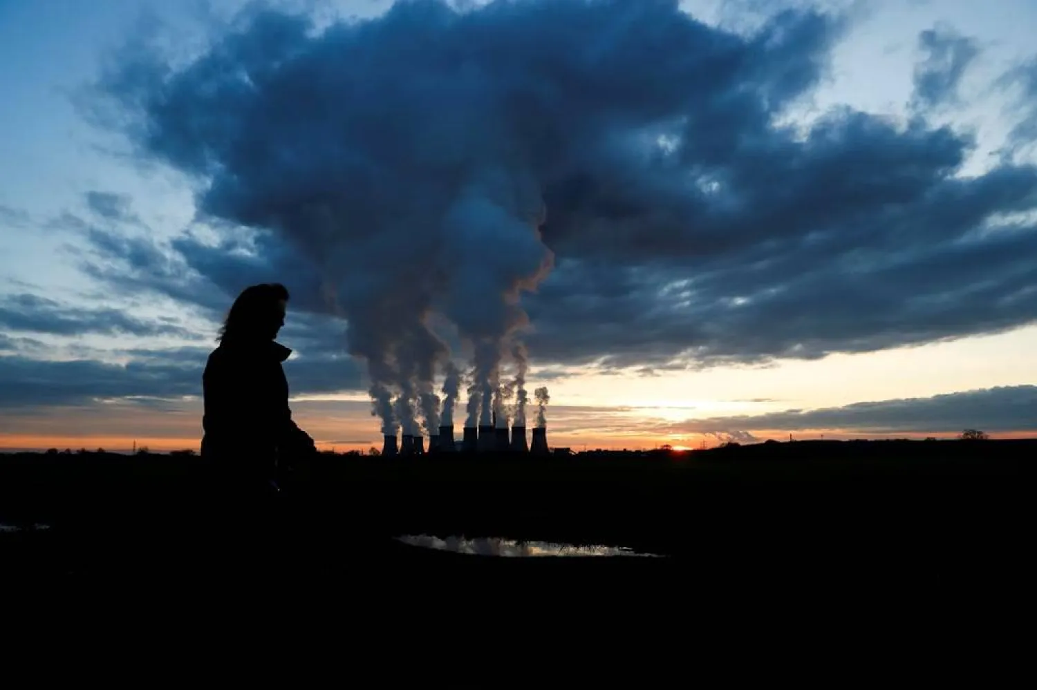 A woman walks a dog past Drax power station during the sunset in Drax, North Yorkshire, Britain, November 27, 2020. (Reuters)