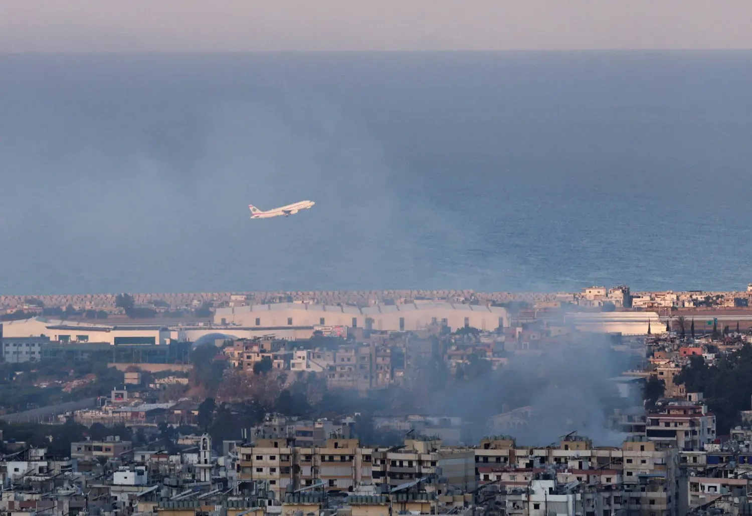 İsrail saldırıları sonucu yükselen dumanlar arasında, Lübnan şirketi "Middle East Airlines"a ait bir uçak "Refik Hariri" havaalanından kalkış yapıyor (Arşiv- Reuters)
