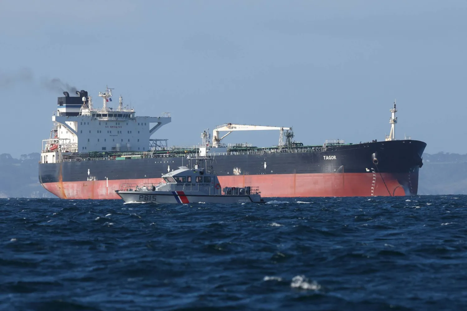 A French Navy vessel sails by the Russian oil tanker "Tagor", suspected of flying a false Cameroonian flag and boarded by the French Navy on May 31, 2026, as it arrives in Douarnenez Bay, western France on June 2, 2026. (AFP)