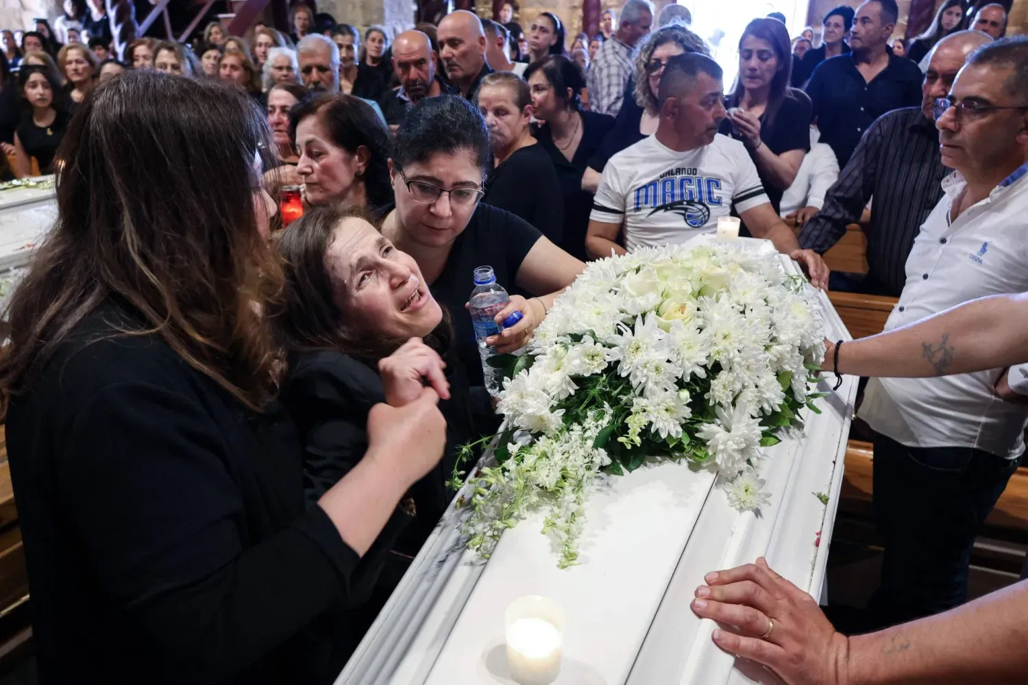 Lübnanlı bir kadın, İsrail'in hava saldırısında hayatını kaybeden baba, kızı ve oğlunun tabutlarının yanında ağlıyor, (AFP)