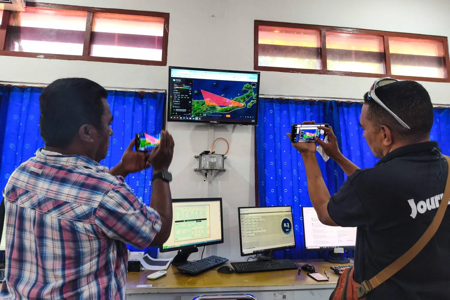 Journalists photograph a screen showing the movement of volcanic ash from Mount Lewotobi Laki-laki at the Meteorology, Climatology and Geophysics Agency (BMKG) office in Maumere, East Nusa Tenggara, Indonesia, on June 5, 2026. (AFP)