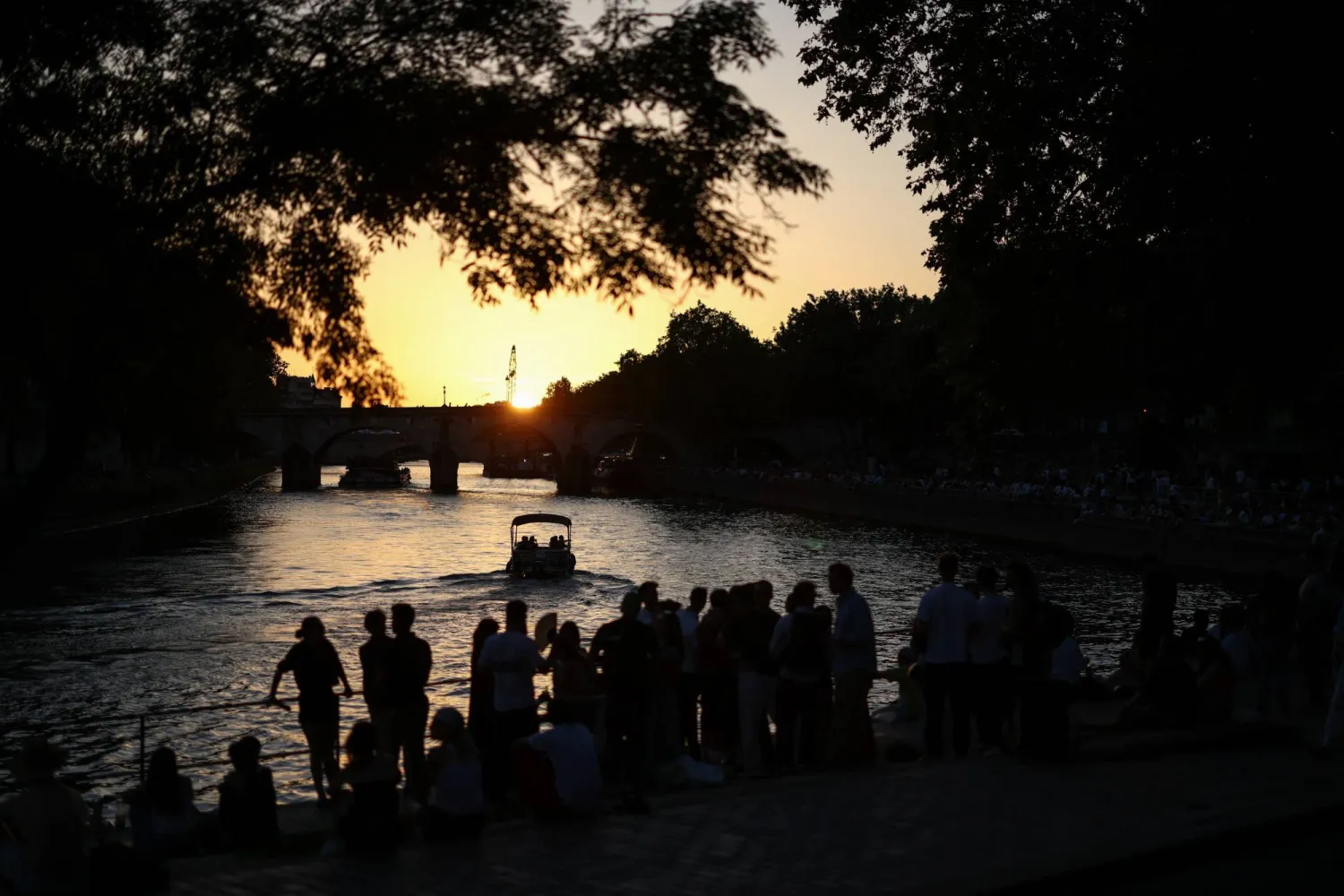 People gather on the banks of the Seine River as the sun sets amid a severe heat wave in Paris, France, May 26, 2026. (Reuters) 