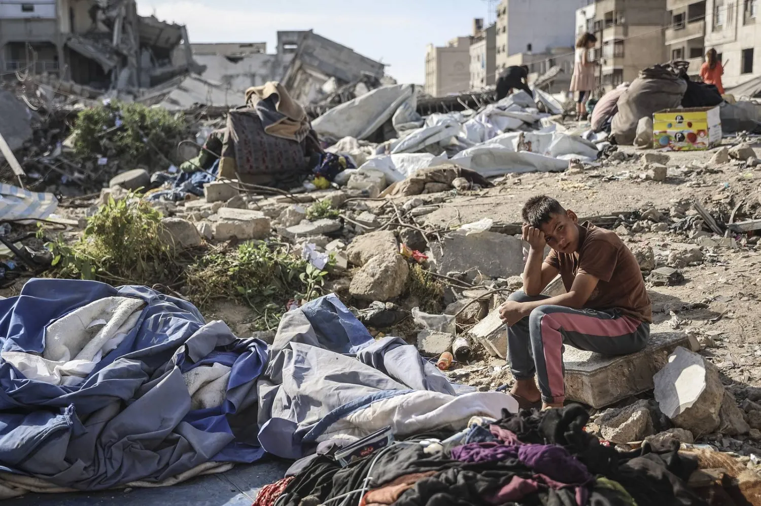  صبي فلسطيني يجلس في موقع غارة عسكرية إسرائيلية استهدفت مباني وخياماً تؤوي عائلات نازحة في غزة (أ.ف.ب)