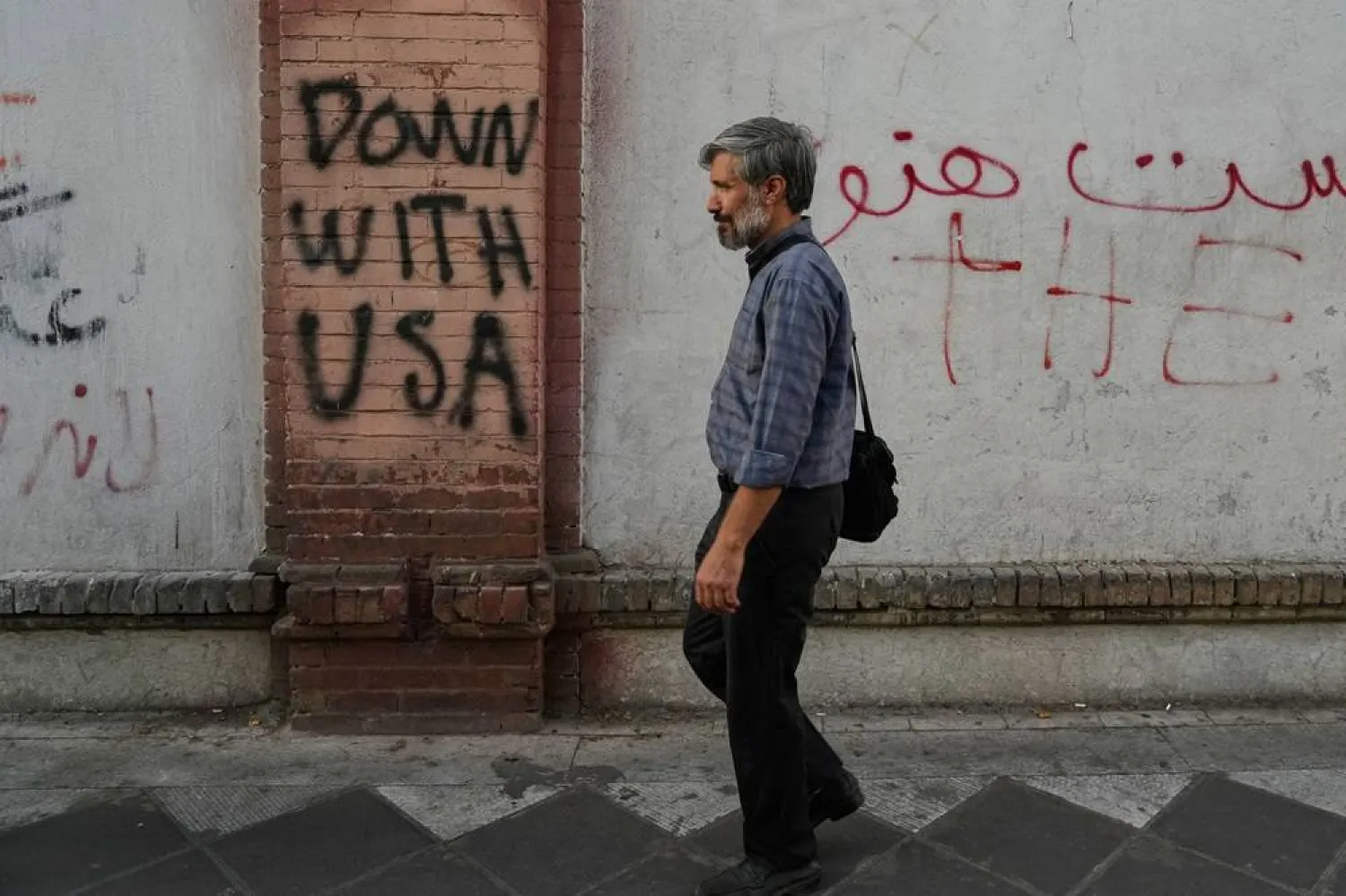  A man walks past anti-US graffiti painted on the wall of the British Embassy in Tehran, Iran, Saturday, June 6, 2026. (AP) 