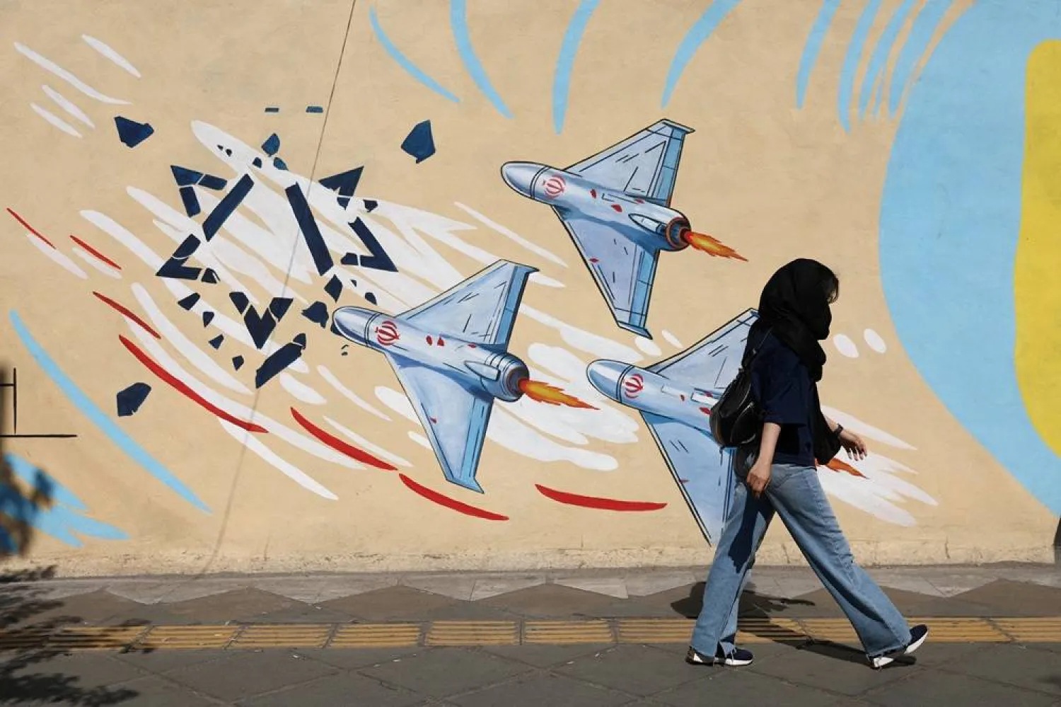 An Iranian woman walks next to an anti-Israeli mural on a street in Tehran, Iran June 8, 2026. Majid Asgaripour/WANA (West Asia News Agency) via Reuters