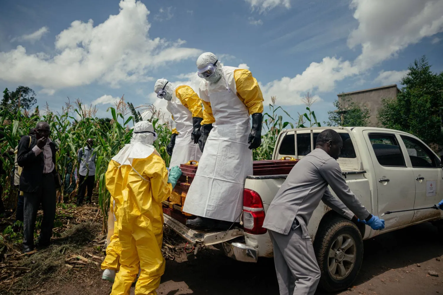 Members of a Congolese Red Cross team wearing personal protective equipment place the coffin of a woman suspected of having died from Ebola virus disease on a pickup truck ahead of her safe burial at her home in Bunia on June 7, 2026. (Photo by Jospin Mwisha / AFP)