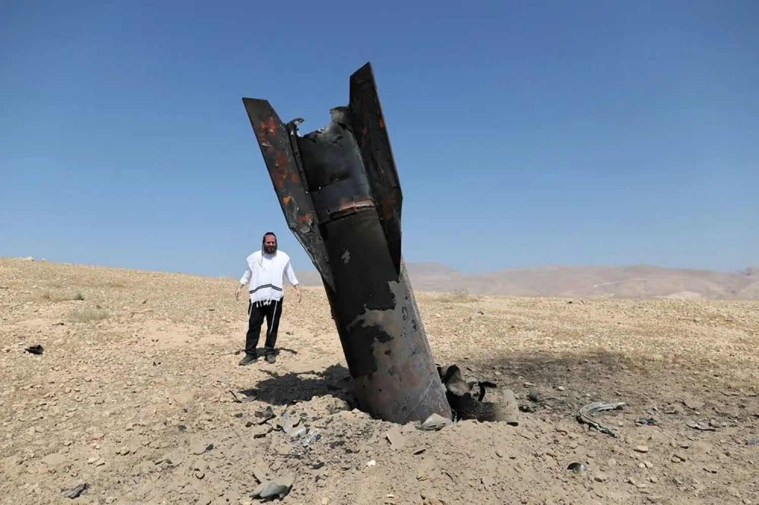  An Israeli ultra-Orthodox Jewish man reacts near a part of a missile protruding from the ground, following strikes from Iran, in the central Israeli-occupied West Bank, June 8, 2026. (Reuters)