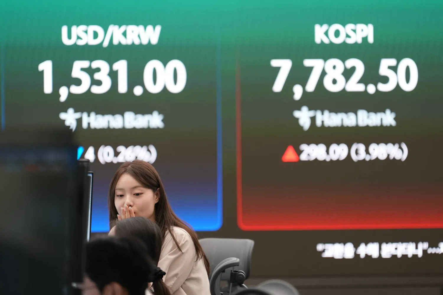 أحد المتعاملين يتحدث بالقرب من شاشات تعرض مؤشر «كوسبي» وسعر صرف العملات الأجنبية بين الدولار والوون الكوري الجنوبي في سيول (أ.ب)