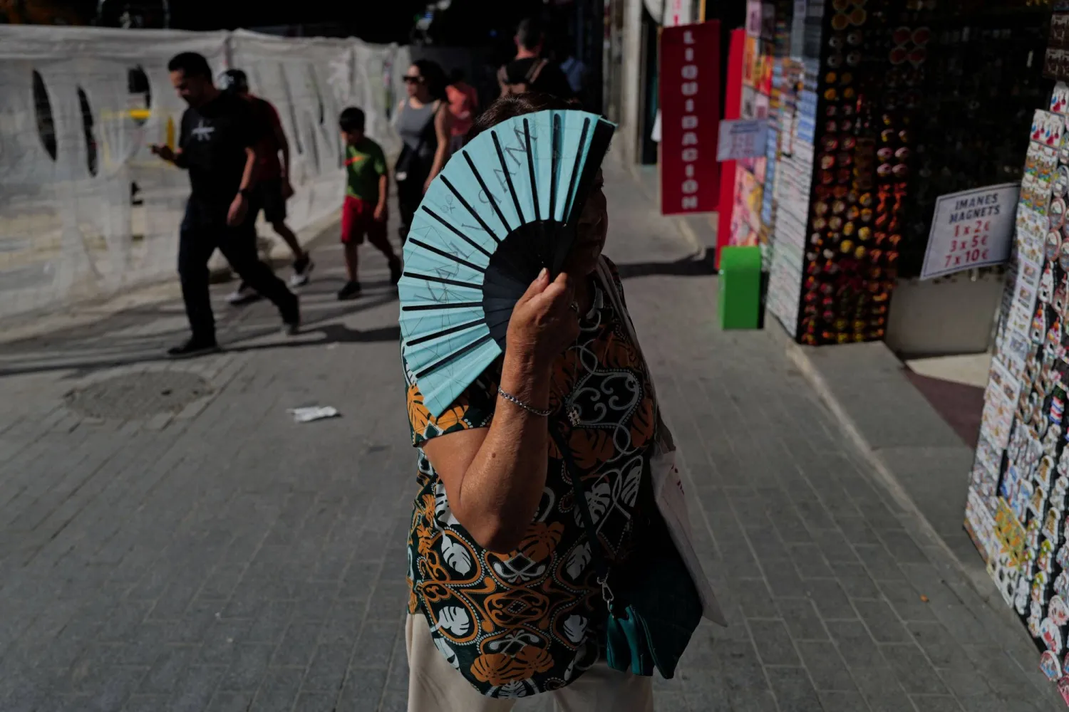 امرأة تحمل هواية يدوية في أثناء سيرها خلال موجة حر ربيعية في مدريد بإسبانيا خلال مايو 2026 (رويترز)