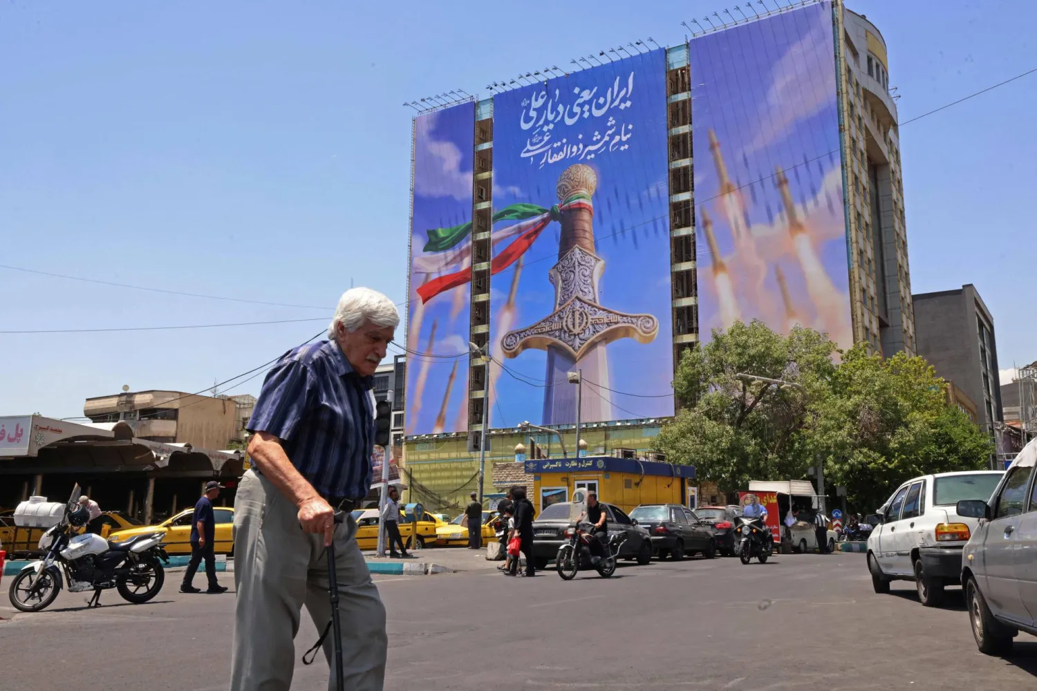 رجل يمر أمام لوحة ضخمة تُظهر صواريخ إيرانية في ساحة ونك بطهران (أ.ف.ب)