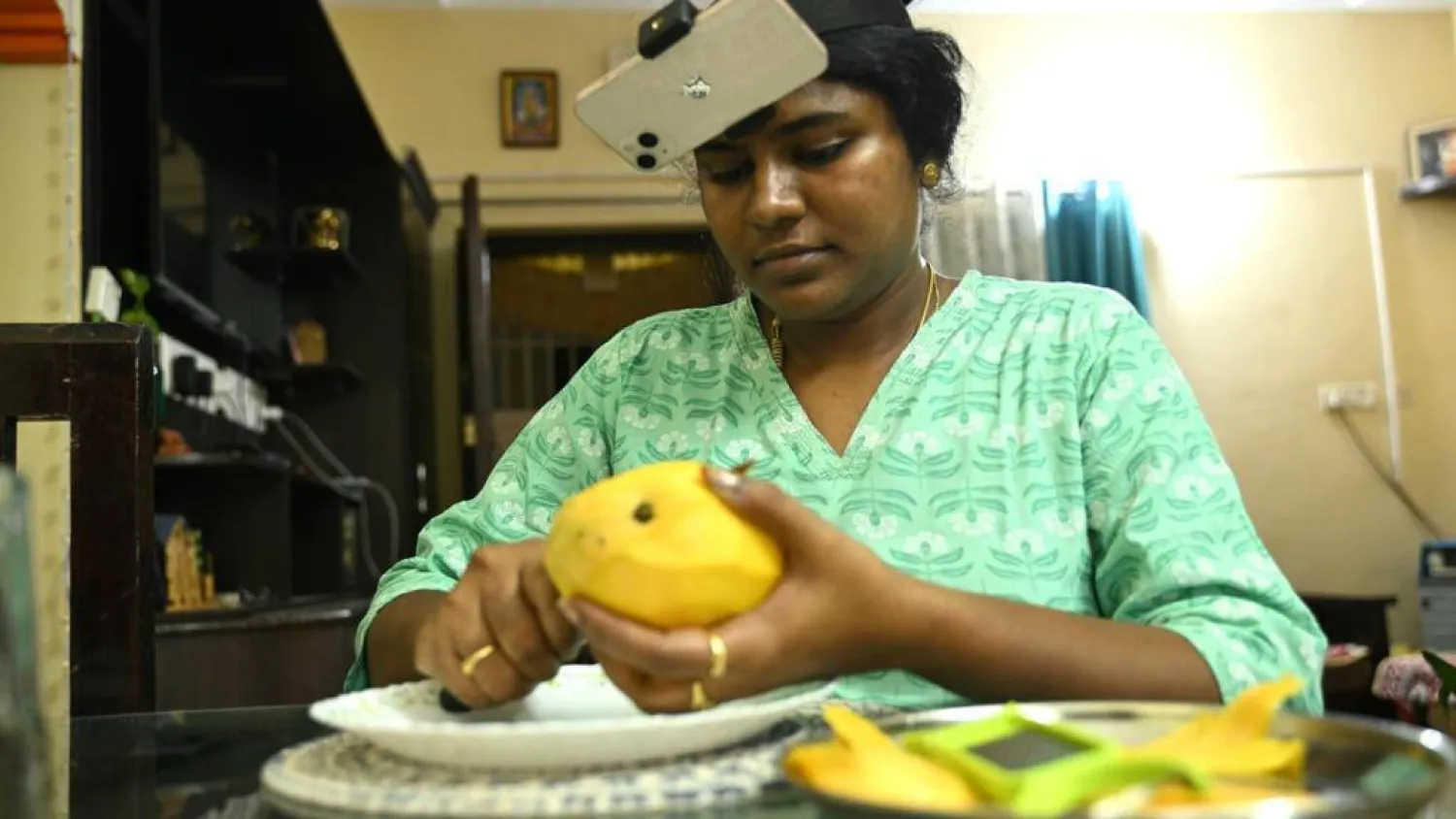 Indian housewife Nagireddy Sriramyachandra wears a smartphone on her head as she records her actions through motion capture while slicing mangoes at her home in Chennai. R.Satish BABU / AFP

