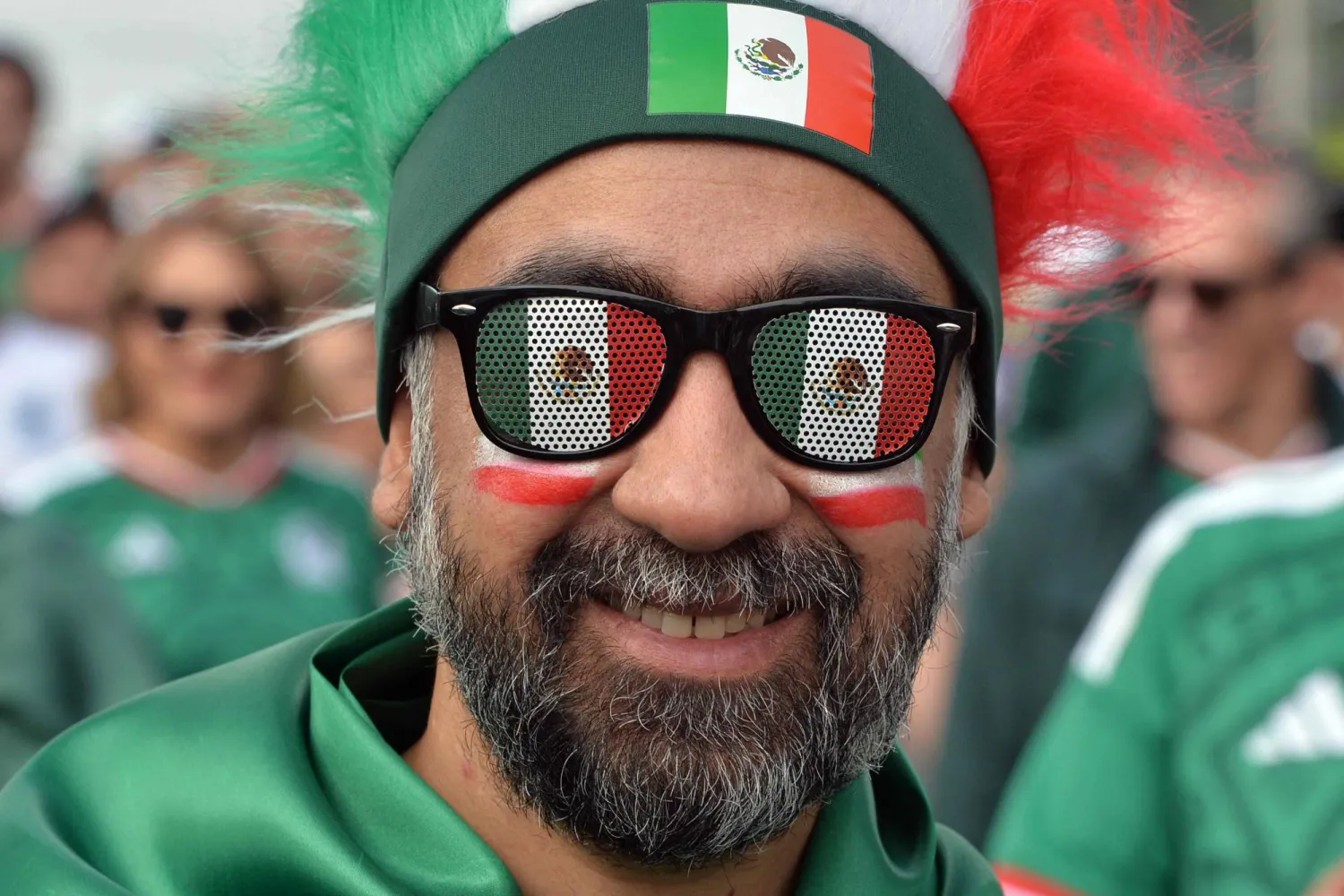 مشجع مكسيكي يتخذ وضعية لالتقاط بنظارته الشمسية (أ.ف.ب)