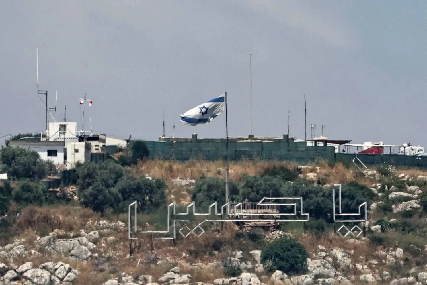 An Israeli army flag flies over the ruins of destroyed buildings in Kfar Kila, southern Lebanon (EPA)