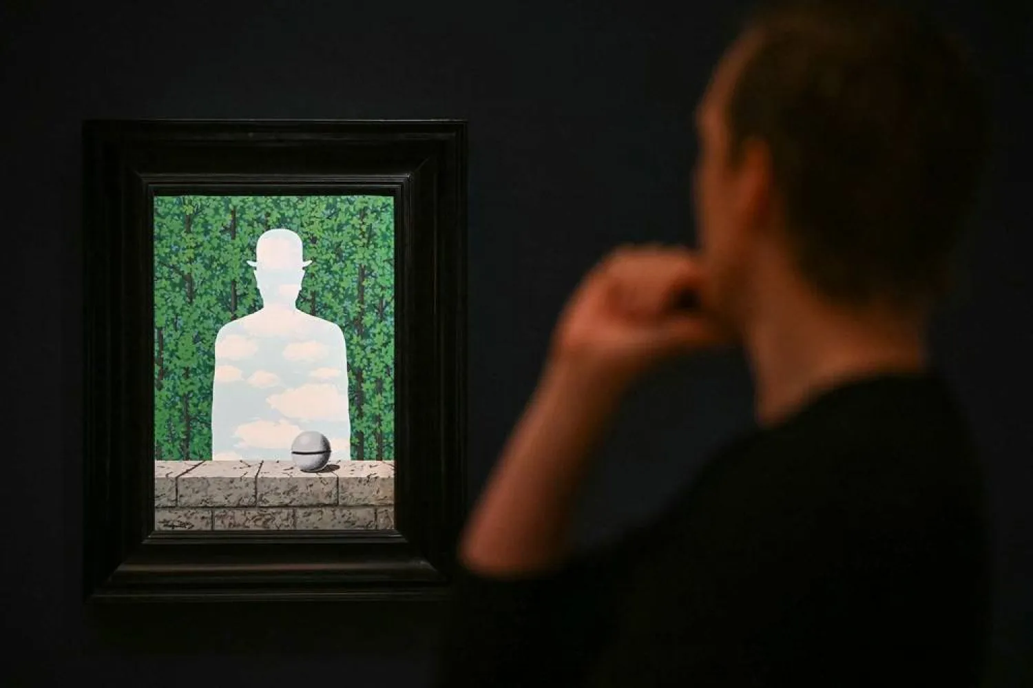 A staff member poses next to René Magritte’s "La Belle promenade", during a media preview by Sotheby's in central London on June 11, 2026, to highlight masterpieces from the Lewis Collection, estimated to be worth some 200 million pounds (267 million USD). (Justin Tallis / AFP) 