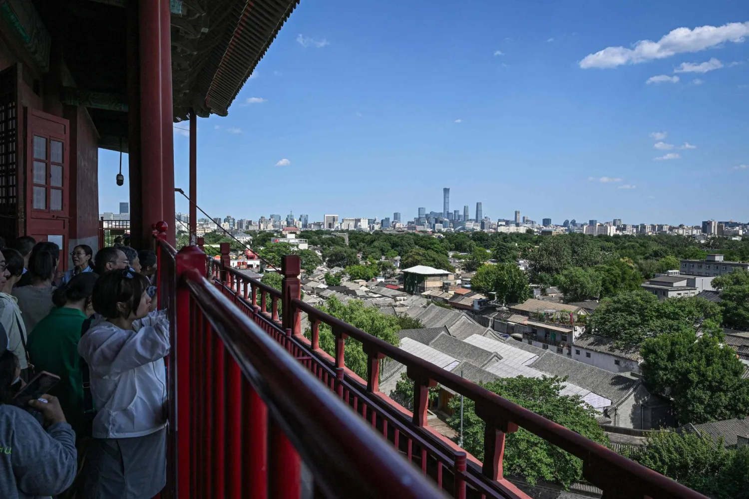 People enjoy the view of the city's skyline and traditional Hutong alleyway houses from the Drum Tower in Beijing on June 5, 2026. (Photo by Jade GAO / AFP)