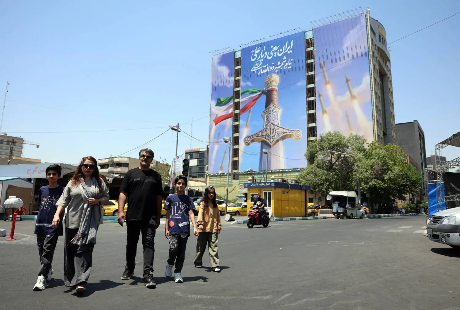 Iranians walk past a large-scale political billboard featuring Iranian missiles and a sword at Vanak square in Tehran, Iran, 11 June 2026.EPA/ABEDIN TAHERKENAREH 