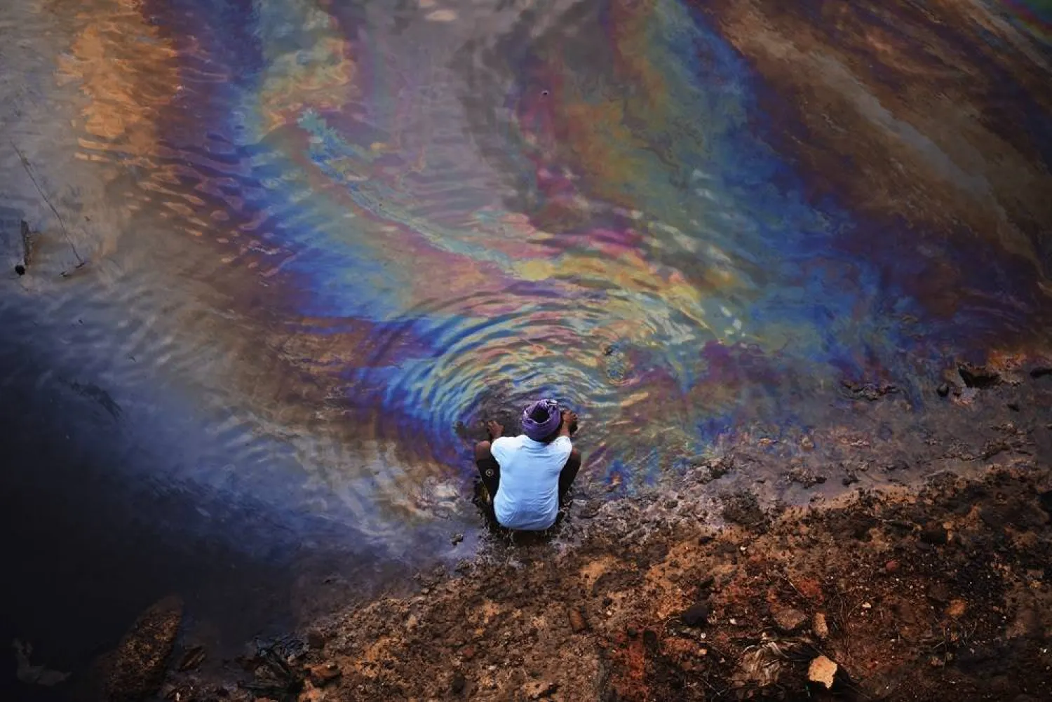 An Indian fisherman washes his hands in the waters of Ennore Creek covered with an oil spill after Cyclone Michaung, in Chennai, India, 11 December 2023. (EPA)