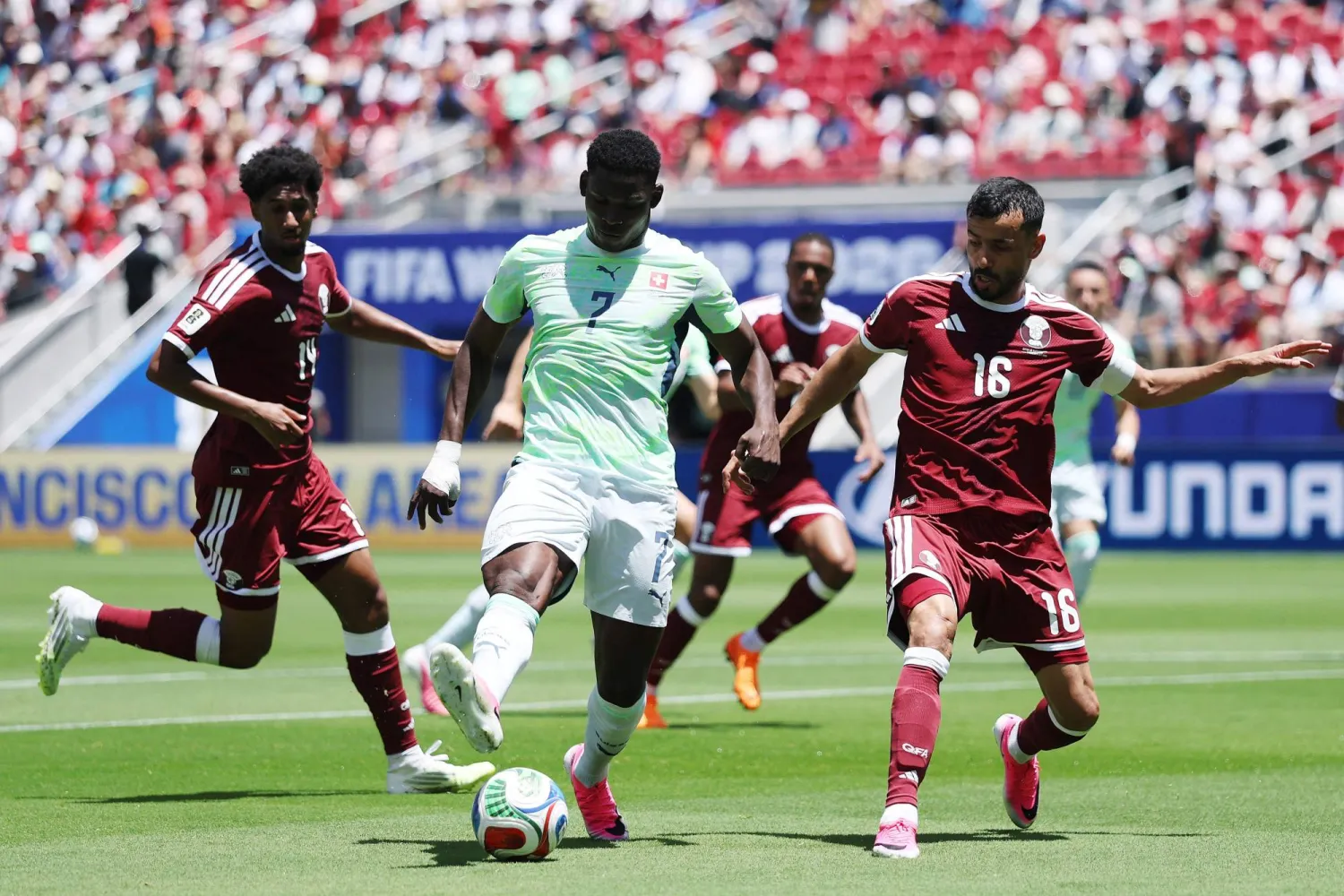 السويسري بريل إمبولو  يسيطر على الكرة تحت ضغط القطري بوعلام خوخي خلال مباراة قطر وسويسرا (أ.ف.ب)