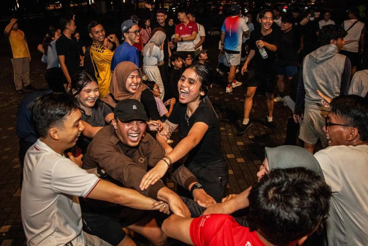 Members of the "Playing Community" group react as they play an Indonesian children's game at the Gelora Bung Karno Stadium compounds in Jakarta on May 22, 2026. (AFP)