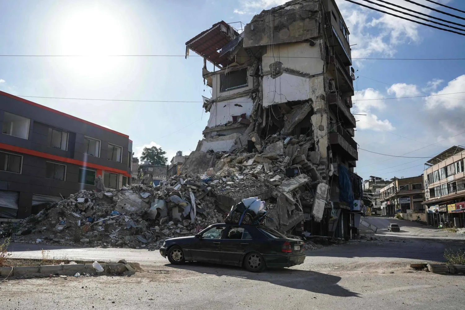 A car loaded with belongings drives past a destroyed building in Nabatieh on June 15, 2026. (AFP)