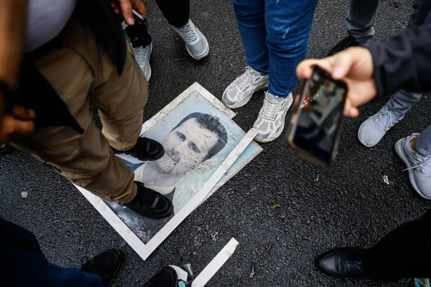 A demonstrator stands on a photograph of President Bashar al-Assad during a protest outside the Syrian consulate in Istanbul, Türkiye, on Dec. 8, 2024. (Getty Images/AFP)