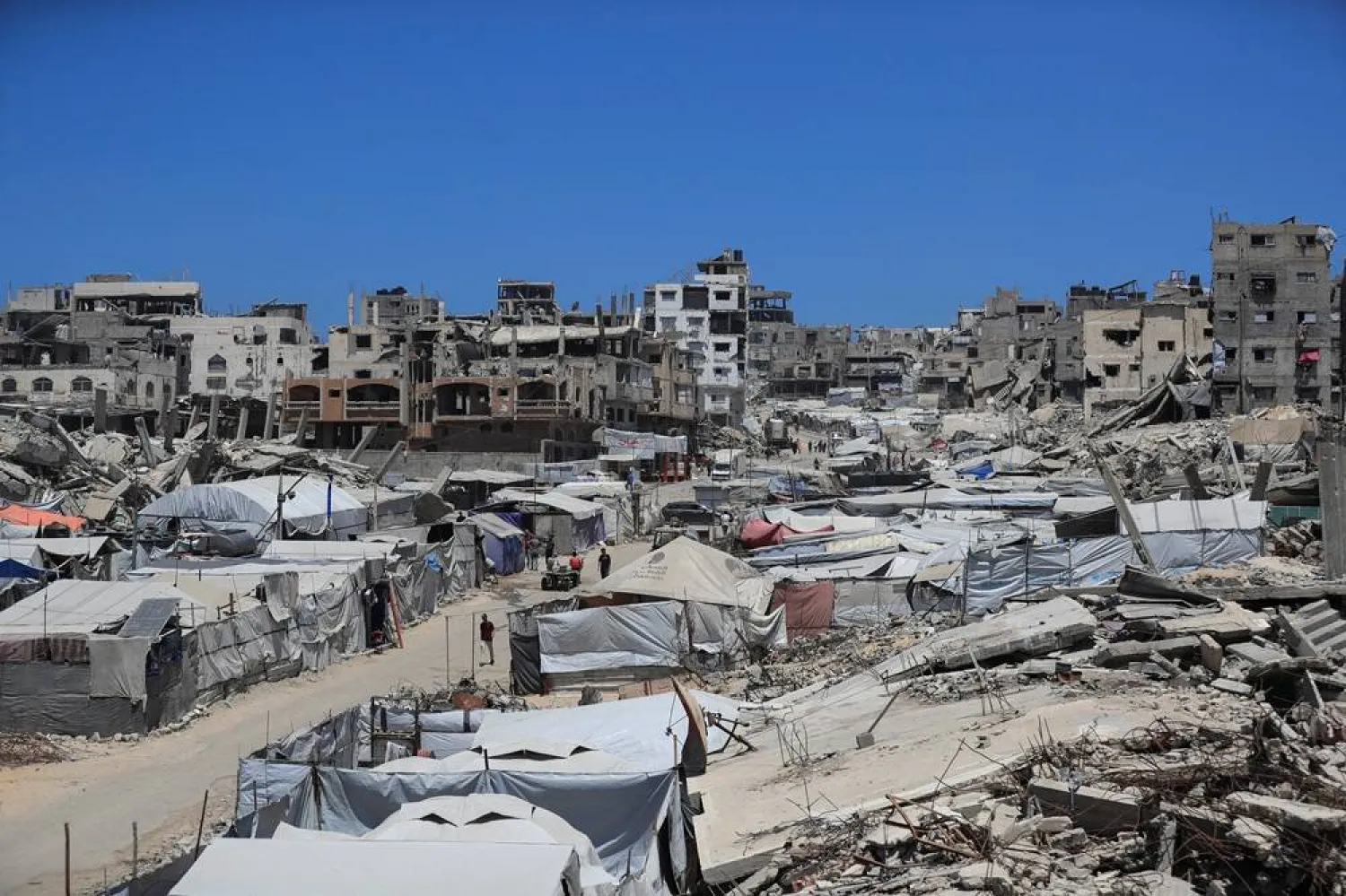  Palestinians make their way past the rubble of residential buildings destroyed during the Israeli offensive as displaced people shelter in tents, in Gaza City, June 15, 2026. (Reuters)
