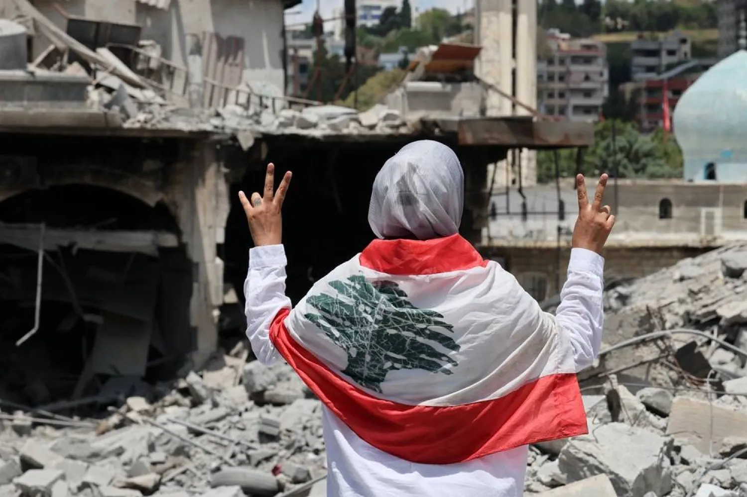 A woman flashes the victory sign next to destroyed buildings following Israeli strikes on the historic old market in the town of Nabatieh, southern Lebanon, 15 June 2026, after the announcement of a US-Iran mediated preliminary framework to end regional military hostilities and lift the naval blockade on the Strait of Hormuz. (EPA)
