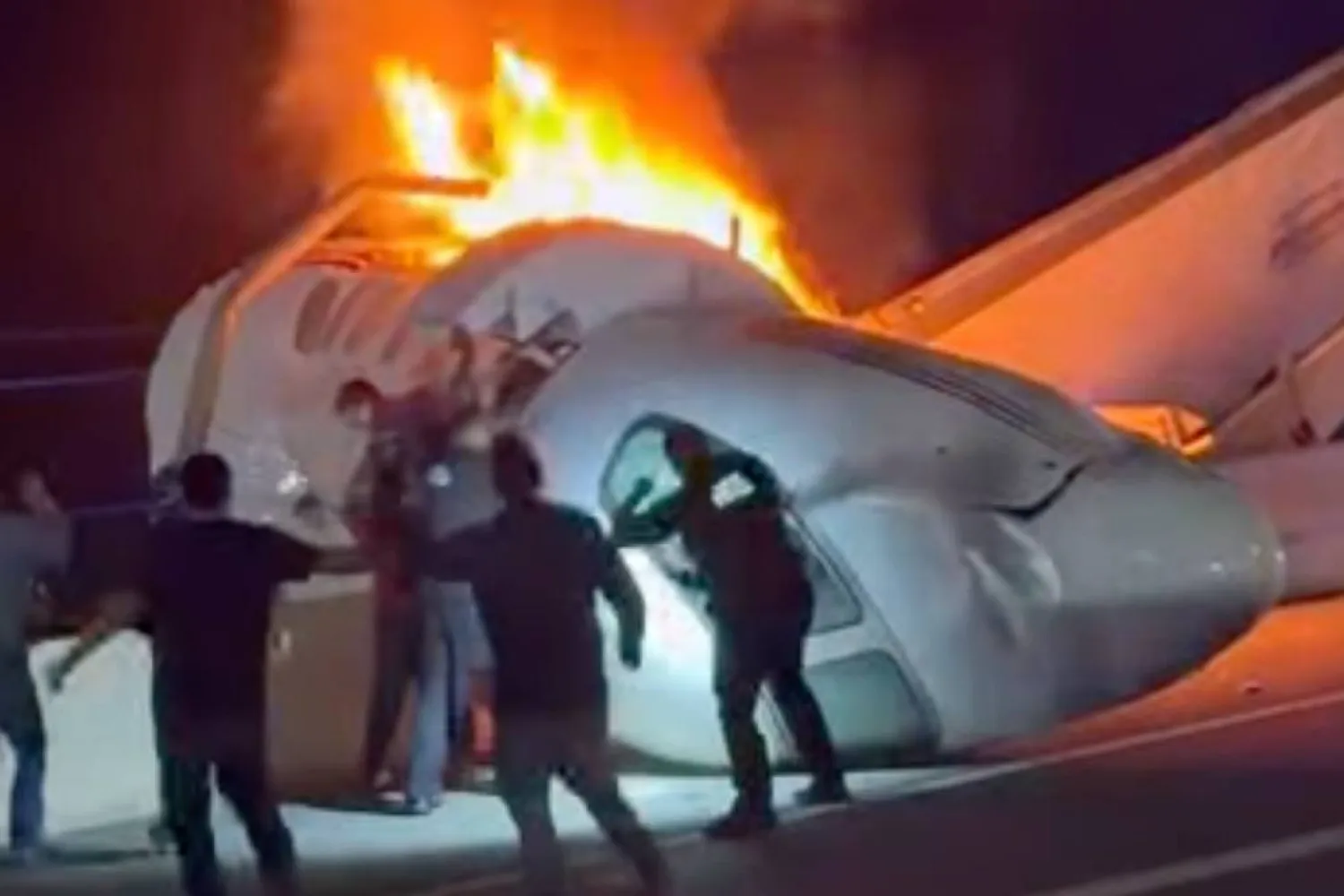A passenger, top, jumps out of a plane after it crashed on a highway as other people help Tuesday, June 16, 2026, in Laredo, Texas. (Zayra Garza via AP)
