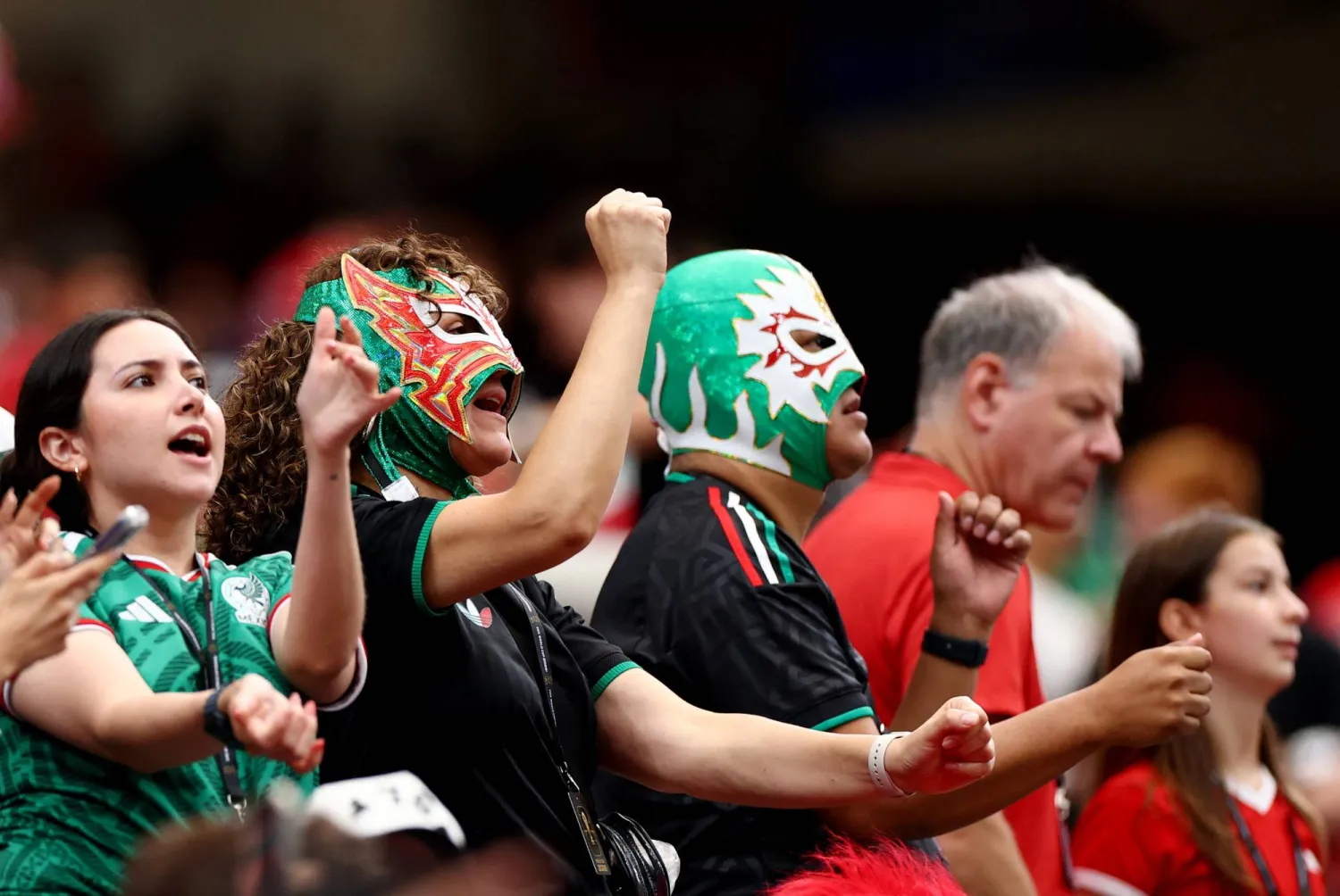 مشجعون يرتدون قمصان منتخب المكسيك وأقنعة داخل مدرجات ملعب هيوستن (رويترز)