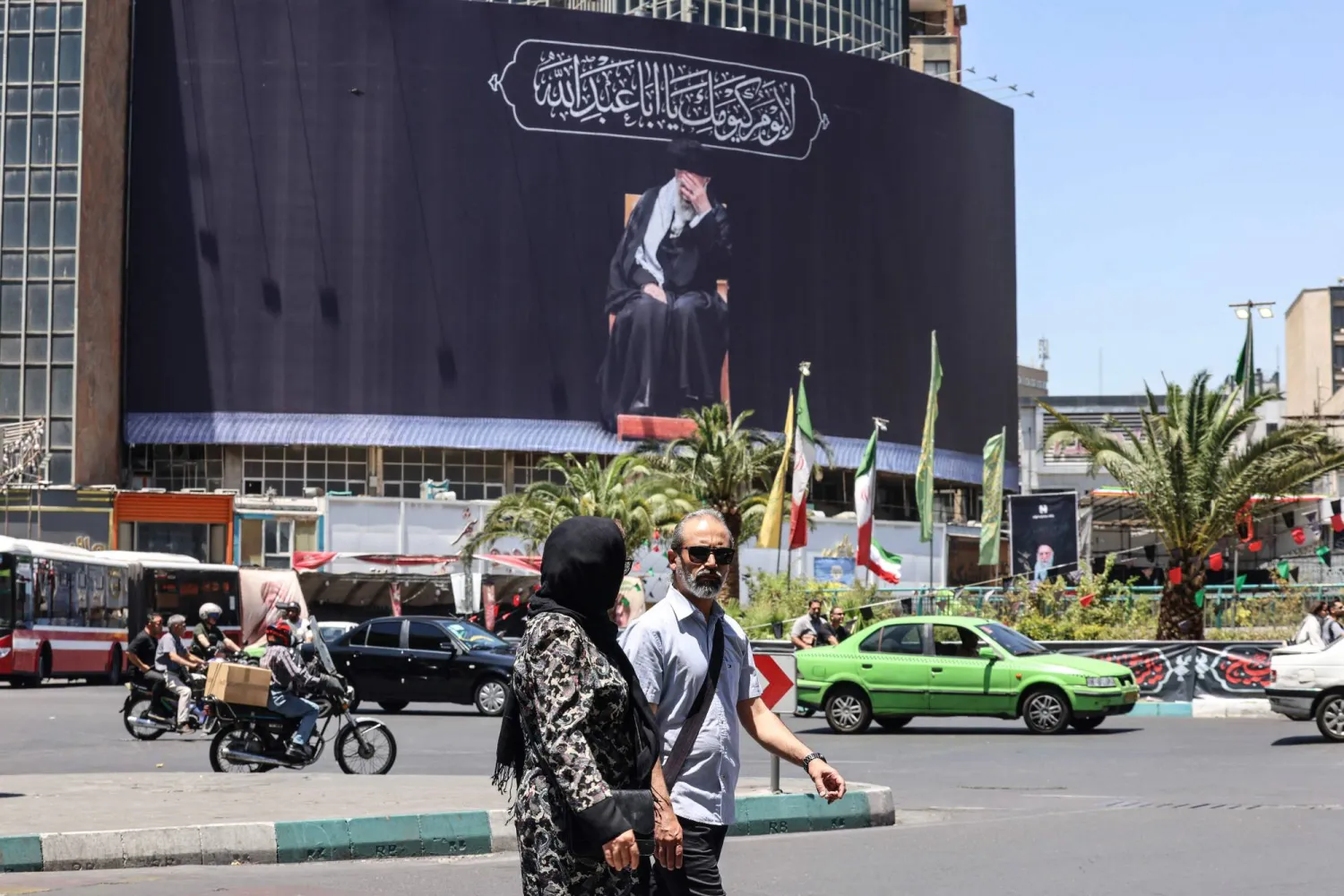 إيرانيون يمرّون أمام لوحة إعلانية تصوّر المرشد الإيراني الراحل علي خامنئي في ساحة في طهران يوم 15 يونيو 2026 (أ.ف.ب)
