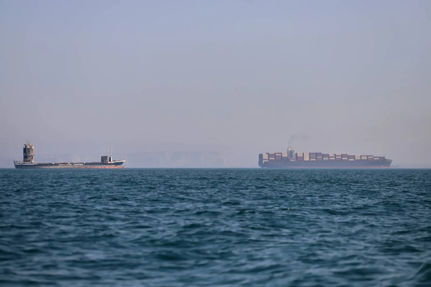 سفينة حاويات وأخرى للشحن في مضيق هرمز (أ.ب)