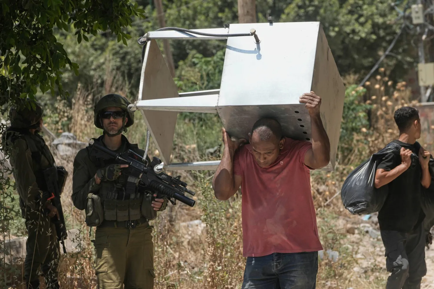 فلسطيني يحمل أغراضه من مخيم طولكرم بالضفة الغربية المحتلة بعدما منح الجيش الإسرائيلي بعض السكان تصريحاً لفترة قصيرة لجمع متعلقاتهم من المنازل التي أجبرهم على النزوح عنها (أ.ب)
